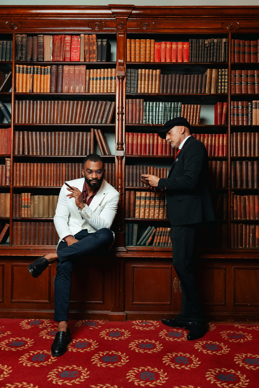 Two Men next to a bookshelf with cigars on hand